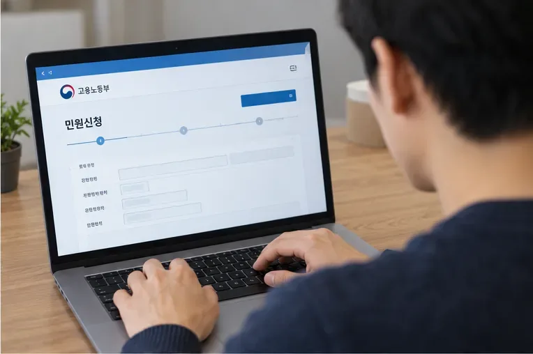 근로자가 노트북에서 고용노동부 민원 신청 화면을 확인하며 임금체불 진정을 준비하는 모습