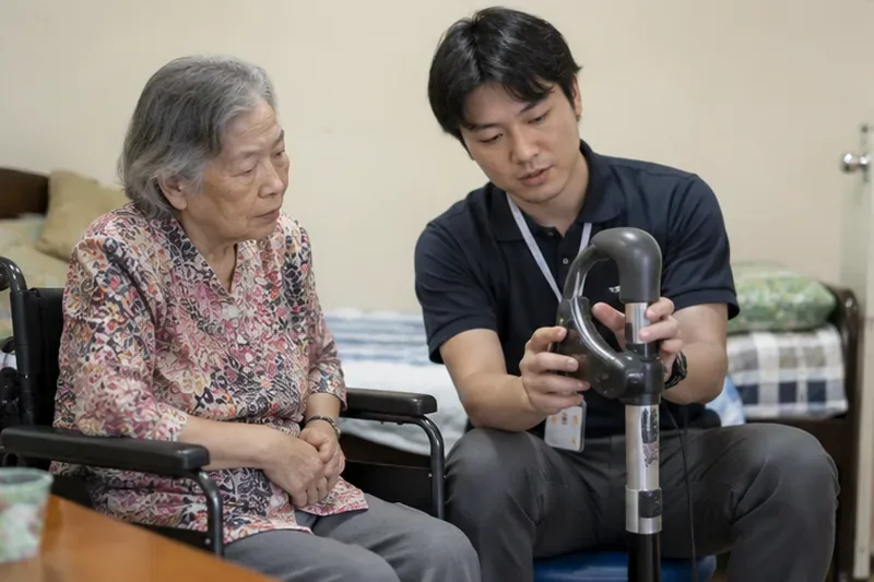輔具評估人員坐在居家空間向長者示範助力設備，長者正仔細觀察操作方式
