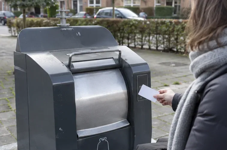 Bewoner houdt een afvalpas bij de kaartlezer van een ondergrondse restafvalcontainer