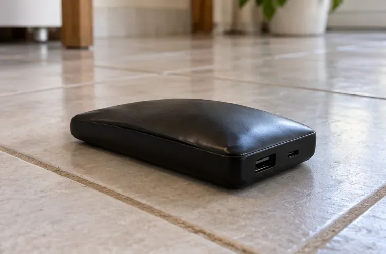 Batterie externe noire posée seule sur un carrelage clair, avec un boîtier légèrement bombé