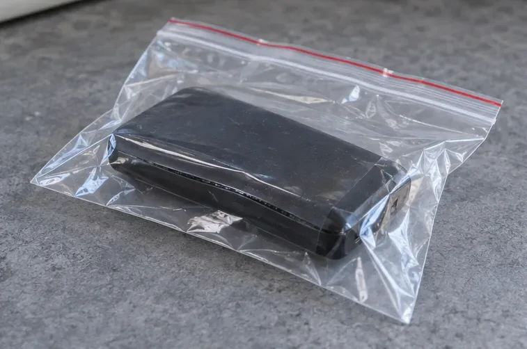 Batterie externe placée dans un sachet plastique transparent à fermeture zip, sans être comprimée.
