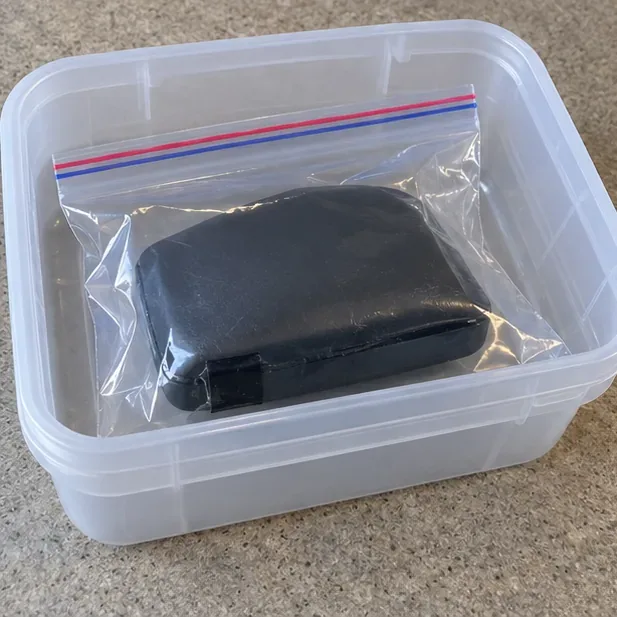 Batterie externe gonflée isolée dans un sac plastique transparent fermé et placée dans un bac de transport