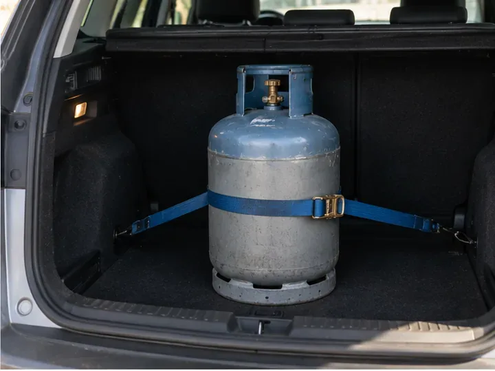 Bouteille de gaz maintenue droite et sanglée dans le coffre d’un véhicule pour éviter qu’elle ne roule pendant le trajet