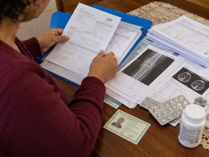 Uma pessoa organiza laudos, exames de imagem, receitas e documentos em uma pasta