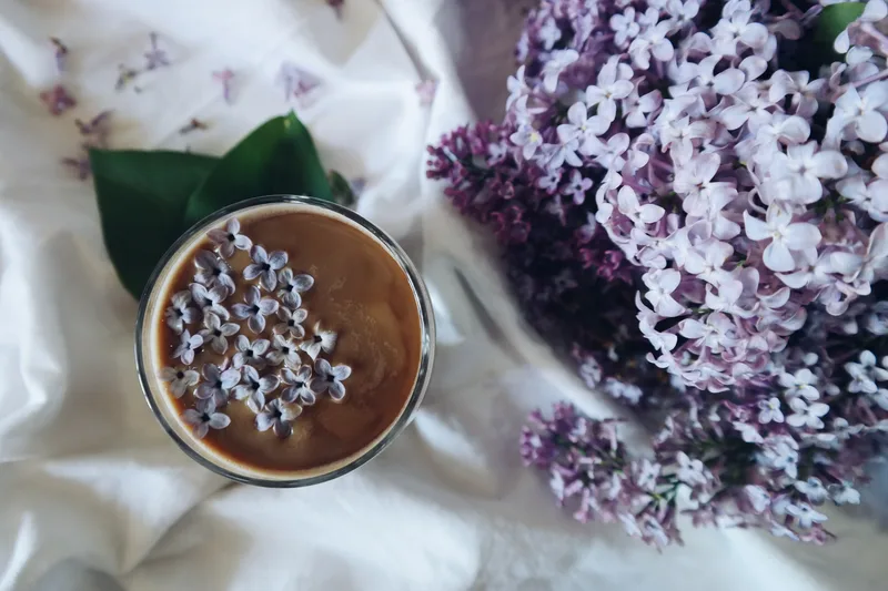Tazza di caffè vista dall’alto con piccoli fiori viola