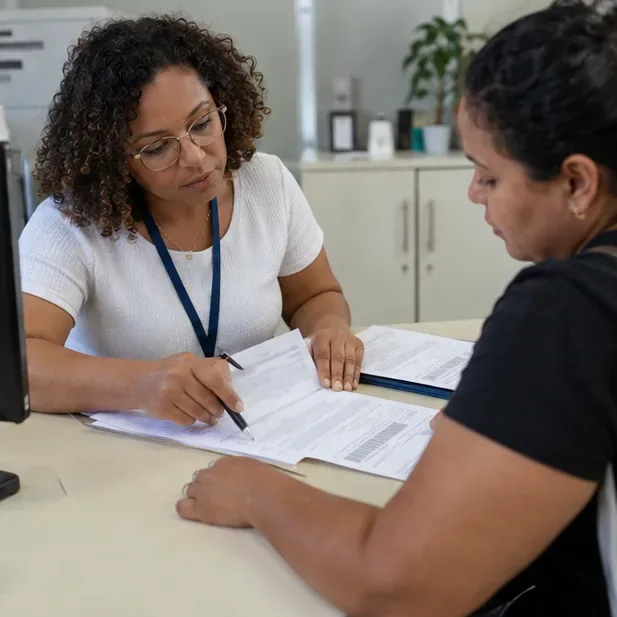 Trabalhadora orienta uma moradora enquanto preenche um formulário com informações da família.