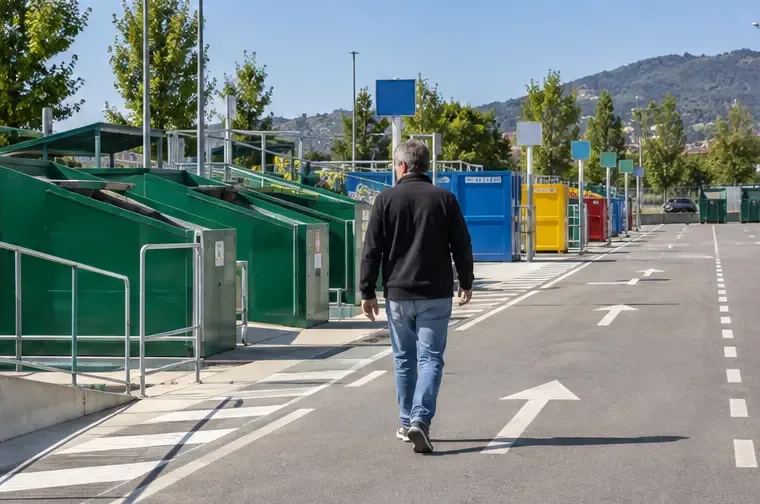 Area ordinata di un centro di raccolta con contenitori separati e frecce bianche sul pavimento