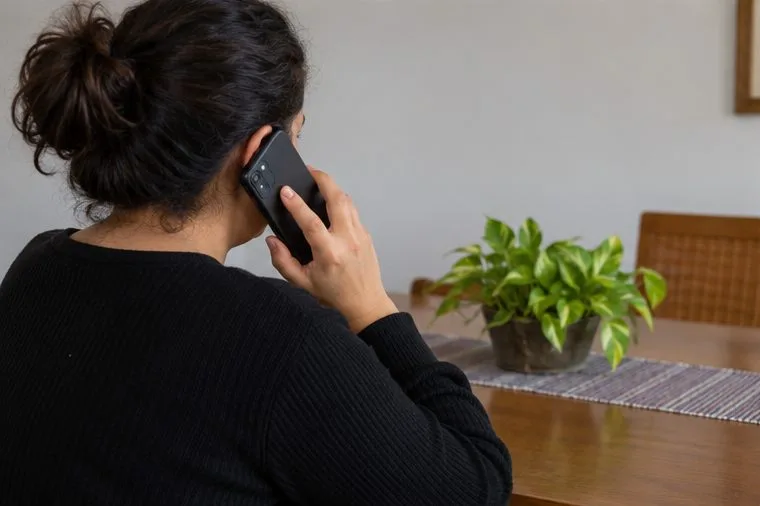 Uma moradora consulta o celular enquanto organiza a solicitação de coleta de resíduos.