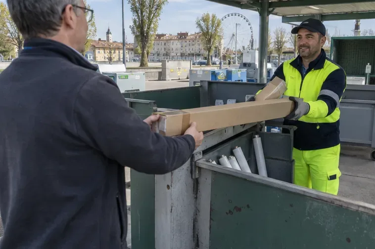 Un addetto di una stazione ecologica riceve una lunga scatola contenente un tubo fluorescente.