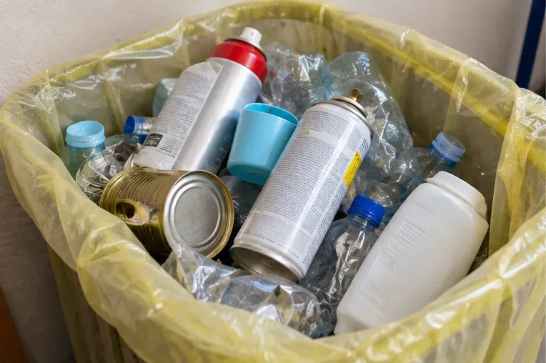 Bombolette spray vuote insieme ad altri imballaggi di plastica e metallo