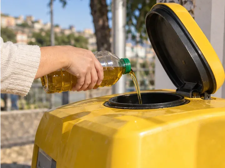 Persona che versa l’olio alimentare usato in un contenitore dedicato per la raccolta degli oli