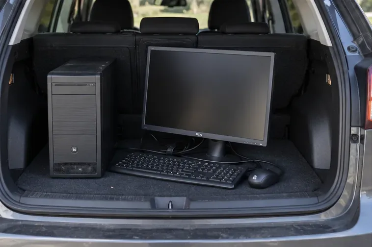 Computer desktop, monitor, tastiera e mouse integri sistemati nel bagagliaio per il trasporto.