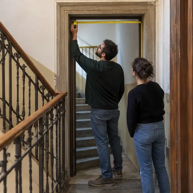 Due persone verificano la larghezza di una porta e il percorso di una scala condominiale