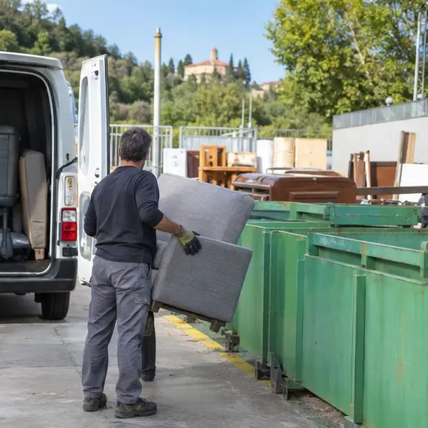 Un operatore scarica un divano da un furgone nell’area per i rifiuti ingombranti di un centro di raccolta