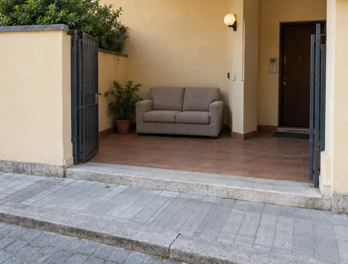 Un divano è collocato all’interno di un cortile rientrante, con il marciapiede esterno libero