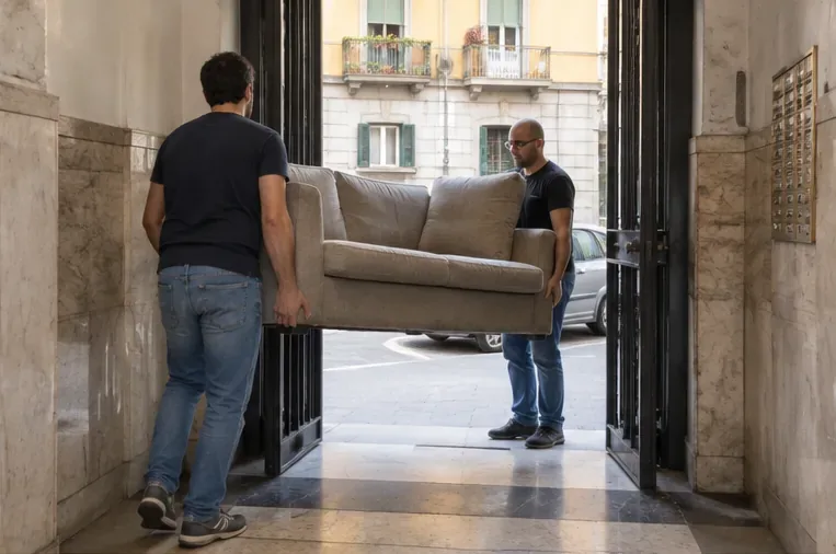 Due persone trasportano con attenzione un divano attraverso l'ingresso di un edificio