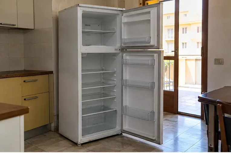 Frigorifero domestico svuotato e con le porte aperte in una cucina