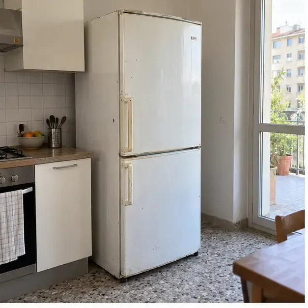 Vecchio frigorifero bianco in una cucina milanese, pronto per essere dismesso