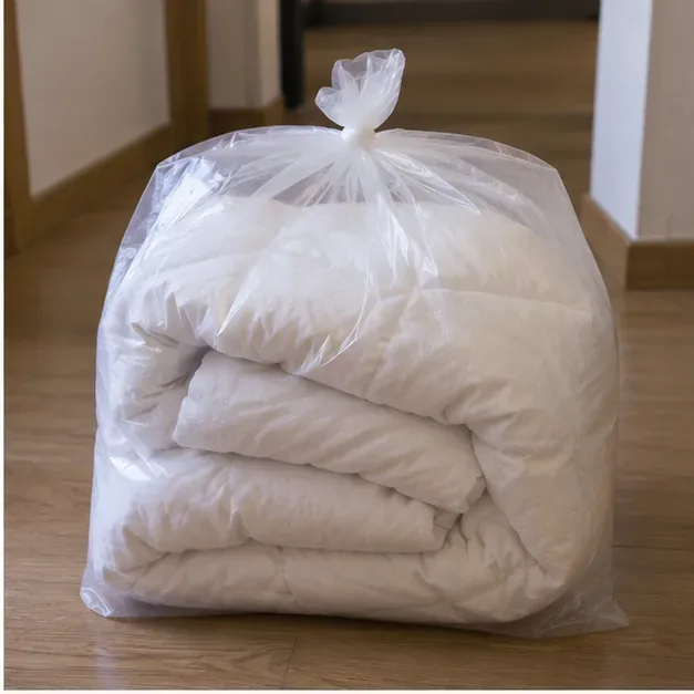 Un piumone bianco piegato e protetto dentro un grande sacco trasparente chiuso