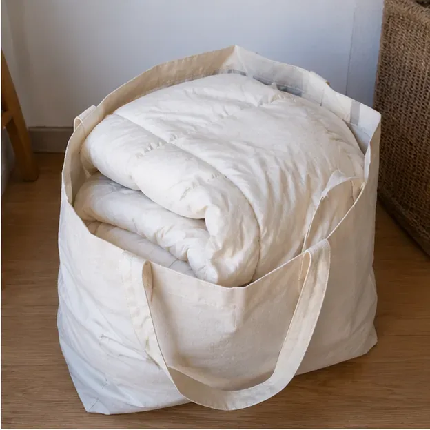 Piumone bianco piegato dentro una grande borsa di tessuto pronta per il trasporto