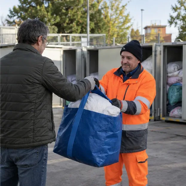 Un addetto riceve una borsa contenente un piumone in un’area di raccolta presidiata