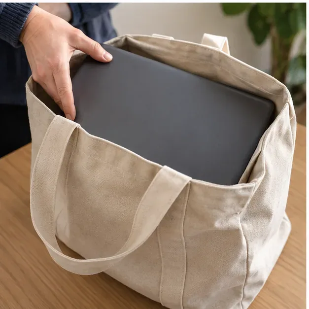 Un portatile chiuso inserito con cura in una borsa di tela per il trasporto al centro di raccolta