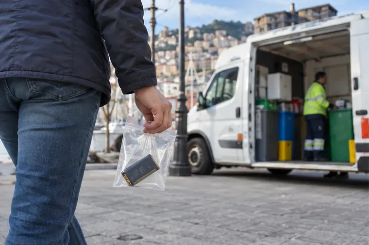 Una persona porta una batteria al litio separata in un sacchetto verso un furgone di raccolta mobile