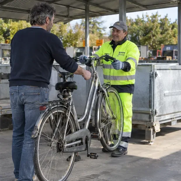 Persona che consegna una bicicletta tradizionale a un operatore in un centro comunale di raccolta