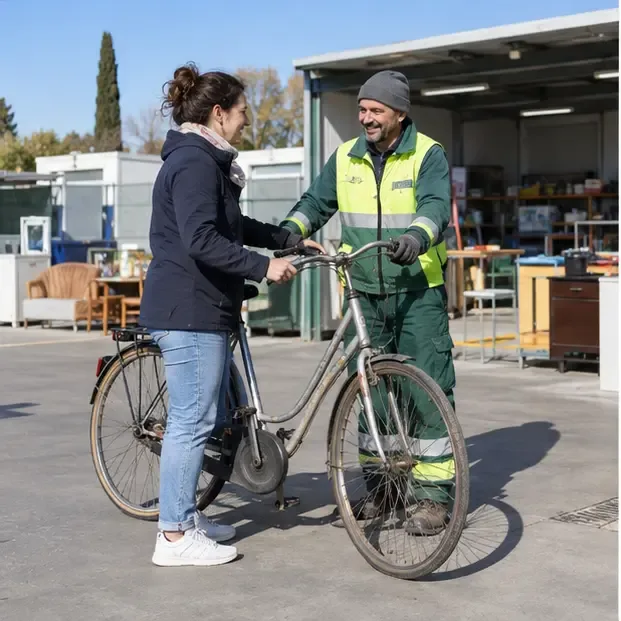Operatore che riceve una bicicletta in un’area di riuso con altri oggetti recuperabili