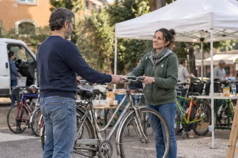 Una bicicletta viene consegnata a una volontaria in un punto di raccolta per il riuso