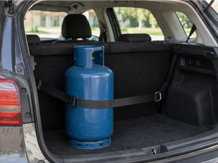 Bombola GPL blu mantenuta verticale e fissata con una cinghia nel vano di carico di un'automobile