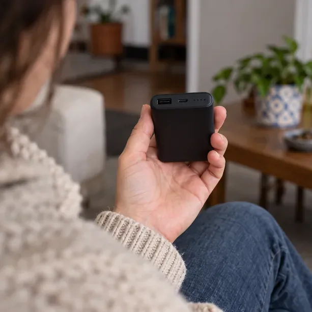Una persona tiene in mano una power bank nera integra e ne controlla le porte USB prima del conferimento