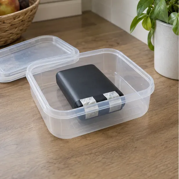 Power bank integra con contatti protetti appoggiata in un contenitore rigido non metallico su un tavolo