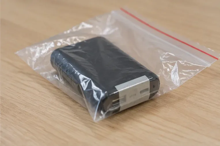 Una power bank nera isolata in un sacchetto trasparente con le connessioni protette