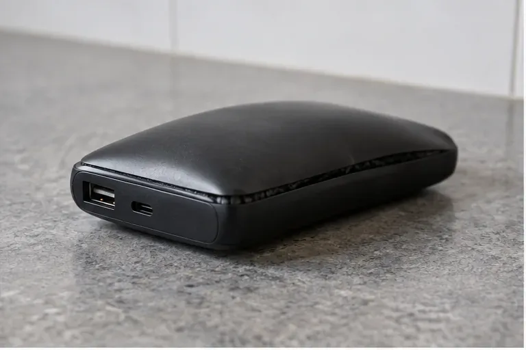 Power bank nera visibilmente rigonfia appoggiata su un piano non combustibile