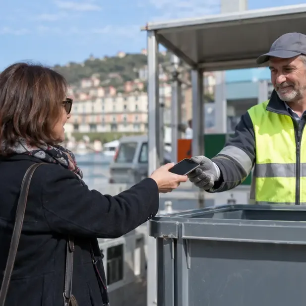 Persona che consegna uno smartphone spento a un operatore in un punto di raccolta