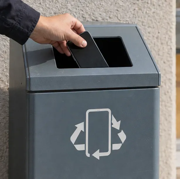Una mano inserisce uno smartphone in un contenitore dedicato alla raccolta dei piccoli dispositivi elettronici.