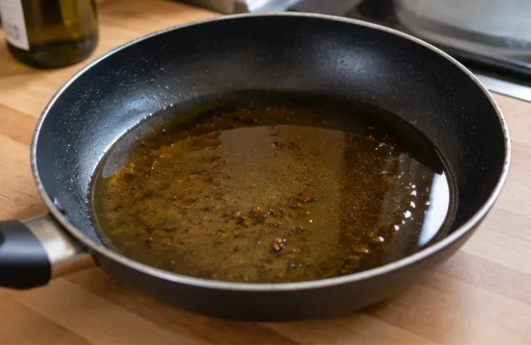 Huile de cuisson refroidissant dans une poêle noire posée sur un plan de travail