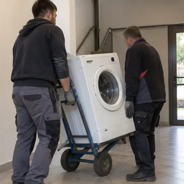 Deux personnes déplacent un lave-linge avec un diable dans un couloir