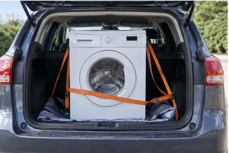 Lave-linge maintenu vertical et sanglé dans le coffre d’une voiture