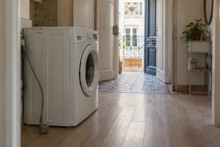 Un lave-linge arrêté près d’un passage dégagé dans un appartement parisien
