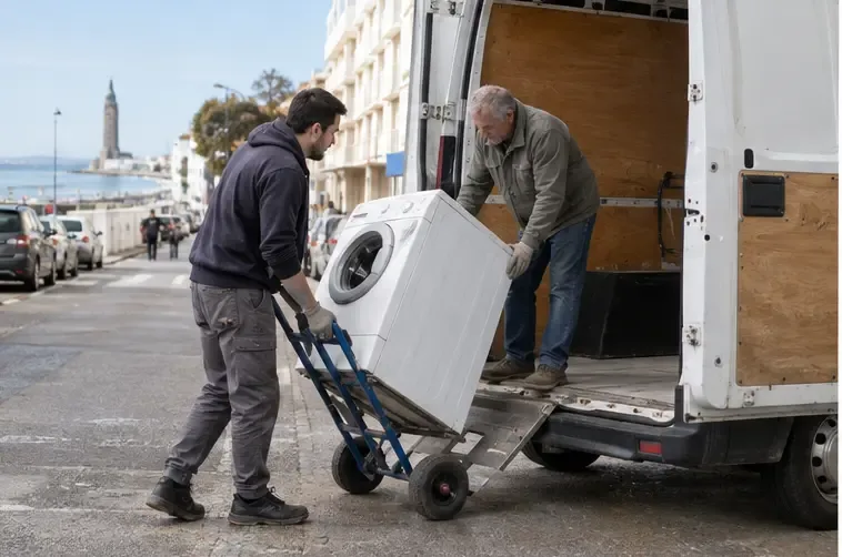 Deux personnes déplacent un lave-linge sur un diable vers un utilitaire