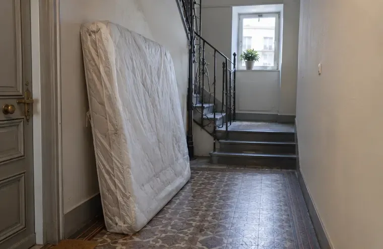 Matelas usagé protégé, posé debout dans le couloir d’un immeuble avant son évacuation