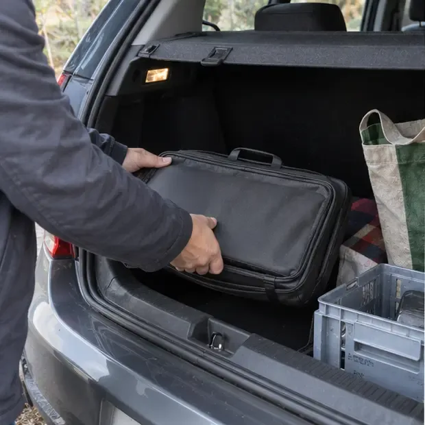 Ordinateur portable rangé dans une housse rembourrée et placé dans le coffre d’une voiture pour un transport vers un point de collecte
