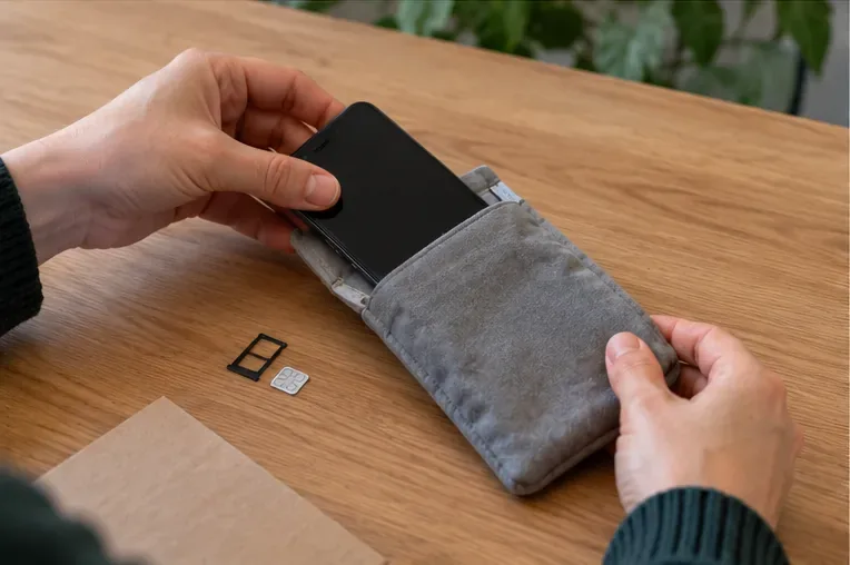 Smartphone placé dans une pochette de protection après retrait d’une carte SIM posée sur une table
