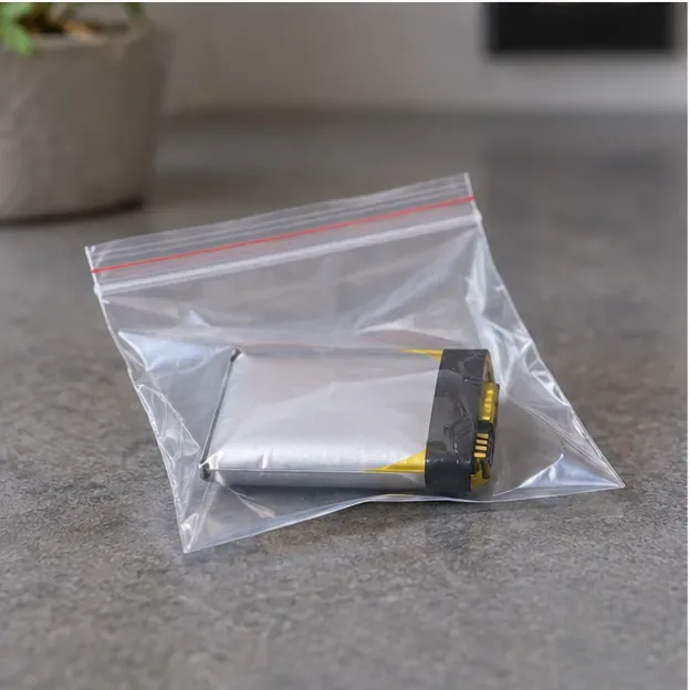 Batterie lithium souple gonflée placée seule dans un sachet plastique transparent fermé sur une surface stable