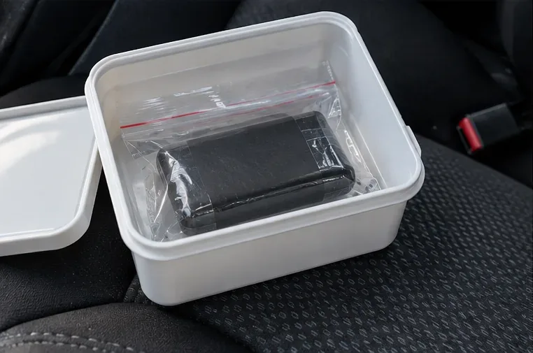 Une batterie externe placée dans un sachet transparent et un petit bac rigide pendant son transport en voiture