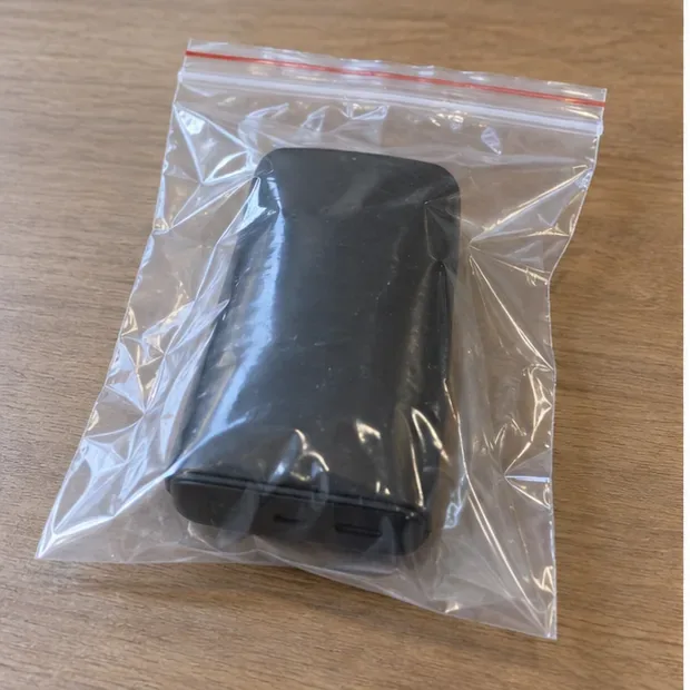Batterie externe gonflée placée seule dans un sachet plastique transparent à fermeture zip