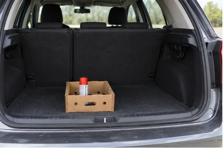 Une bombe aérosol maintenue debout dans une petite boîte placée dans le coffre d’une voiture