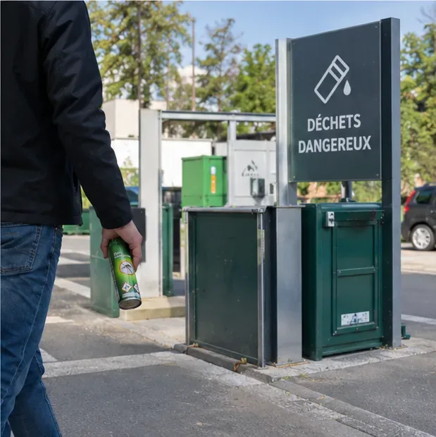 Une personne apporte une bombe aérosol dangereuse vers un point de collecte spécialisé portant l’indication Déchets dangereux.